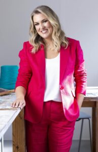 Portrait of Sara Davies in a pink suit.