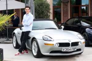 Paris Brosnan posing with a silver BMW Z8.