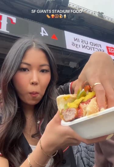 Itskarlabb eats a hot dog at a baseball game.