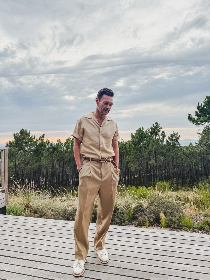 Ryan Seacrest in a tan suit, standing on a deck.
