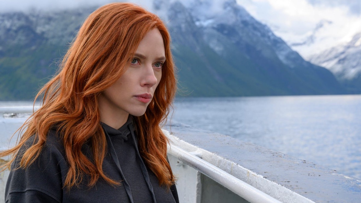 Scarlett Johansson with long red hair on a boat in a lake near a snowy mountain