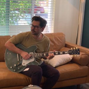 Man playing a grey electric guitar.