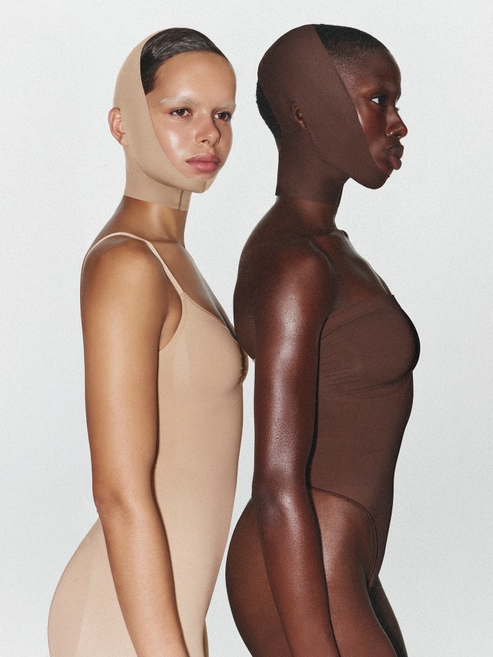 Two models wearing SKIMS bodysuits and face masks.