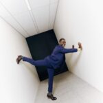 Sterling K. Brown in a blue suit in a blank hallway.