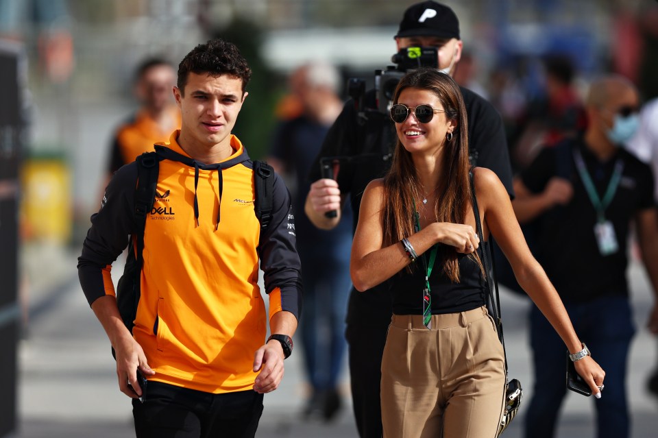 Lando Norris and his girlfriend walking in the paddock.
