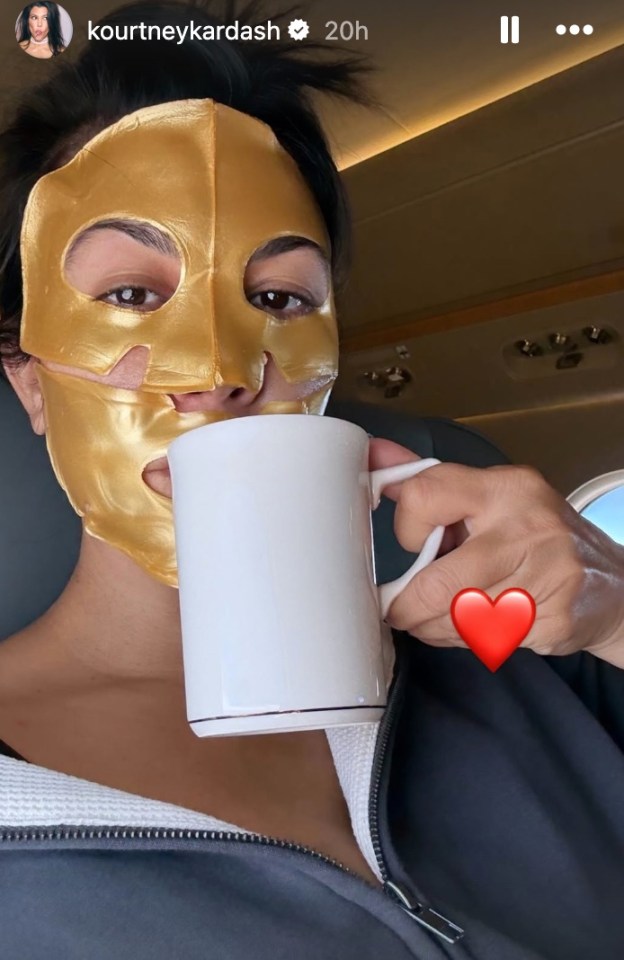 Kourtney Kardashian wearing a gold face mask and drinking from a mug.