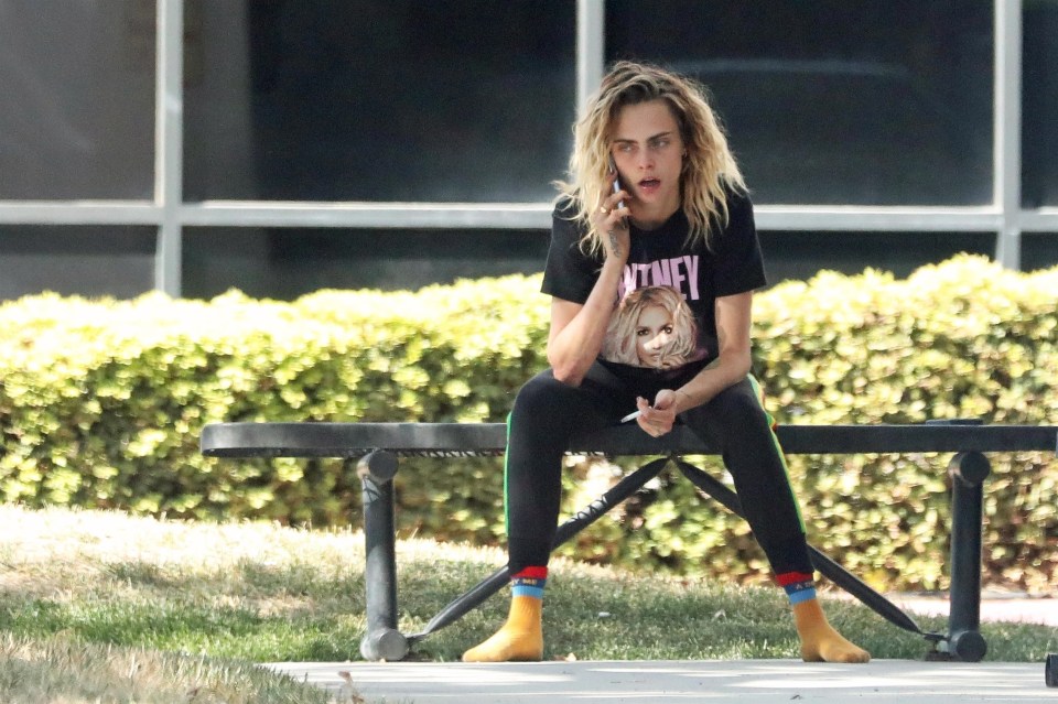 Cara Delevingne on a park bench, on a phone call.