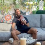 Man holding a baby on a couch outdoors.