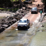 truck passes crocodiles at Australia's Cahills Crossing in the Northern Territory