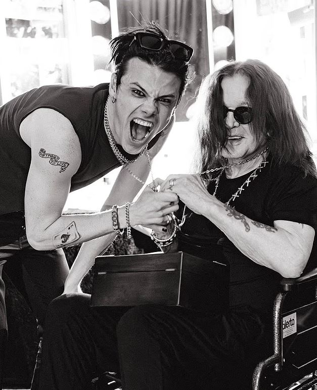 Black and white photo of Ozzy Osbourne receiving a gift from a younger man.