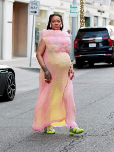 Rihanna walking in Los Angeles wearing a pink dress and Puma sneakers.