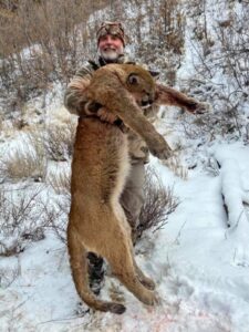 Asher Watkins holds up a mountain lion that he killed.